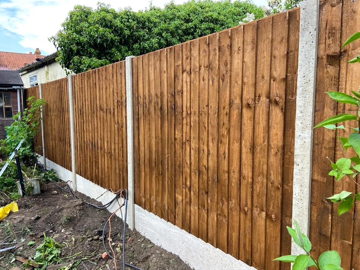 New feather-edge close-board fence stained dark brown on concrete posts and gravel boards