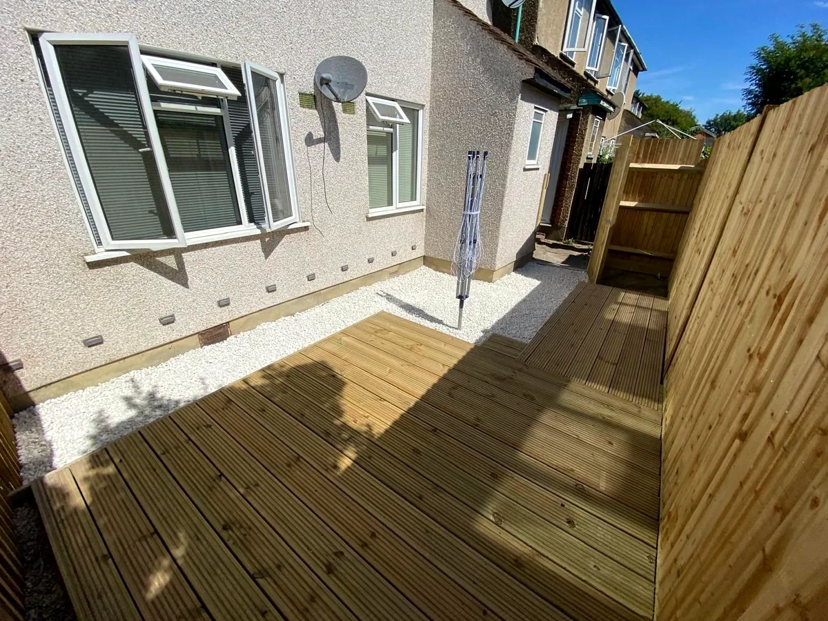 Softwood timber decking with a white-gravel border, a feather-edge fence and house behind