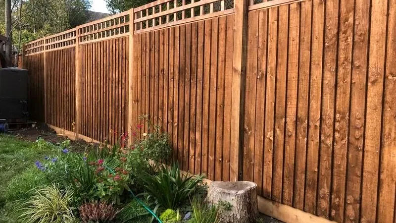 Feather-edge close-board fence topped with square trellis behind a planted flower border