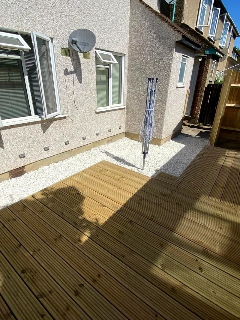 Softwood timber decking with a white-gravel border, a feather-edge fence and house behind