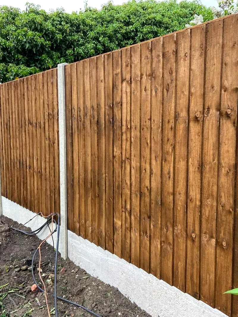 New feather-edge close-board fence stained dark brown on concrete posts and gravel boards